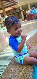 Cute boy looking away while sitting on poolside