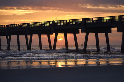 Silhouette pier over sea against sky during sunset