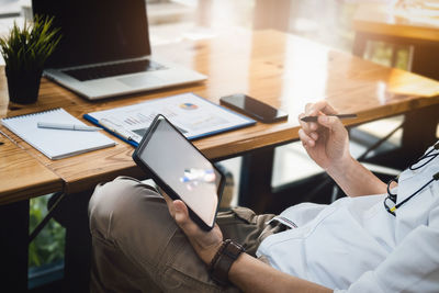 Midsection of man using digital tablet on table