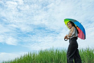 Side view of woman standing on field against sky