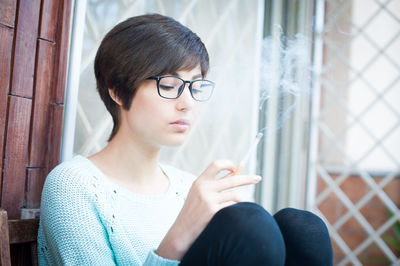 Woman looking away while sitting on window