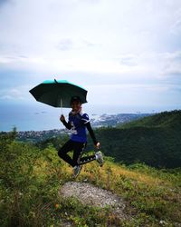 Woman holding umbrella on land against sky