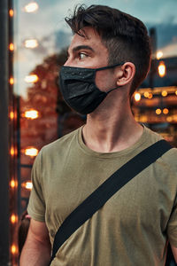 Young man wearing mask looking away outdoors