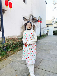 Portrait of young woman standing on footpath