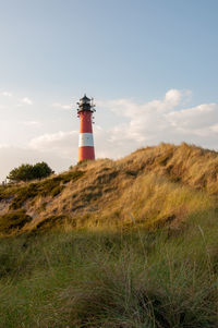 Lighthouse on field against sky