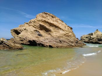 Rock formations on shore against blue sky