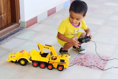 Boy playing with toy bulldozer on porch