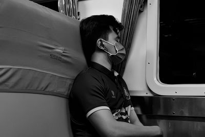 Side view of young man looking through window