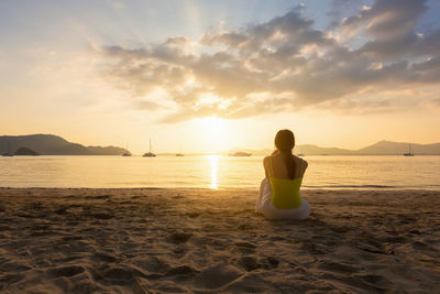 Rear view of woman sitting on beach