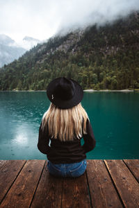 Rear view of woman on pier over lake against mountain