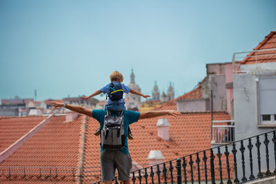 Low angle view of man standing on railing against clear sky