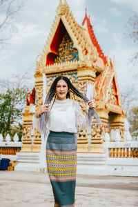 Portrait of young woman standing against temple