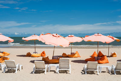 Chairs and parasols on beach against sky