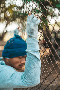 Portrait of boy seen through chainlink fence