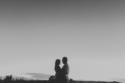 Silhouette couple embracing while standing against clear sky