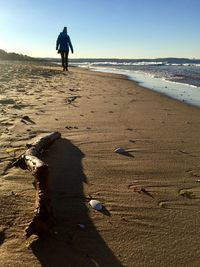 Full length of man walking on beach against clear sky