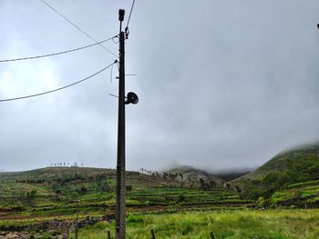 Electricity pylon on field against sky