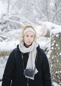 Portrait of young woman standing in snow during winter