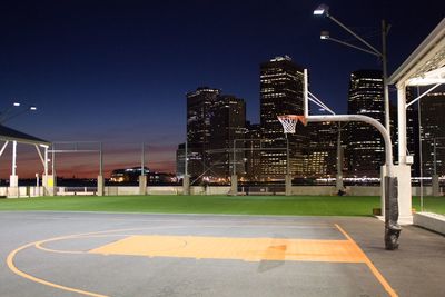 Illuminated basketball court against sky in city