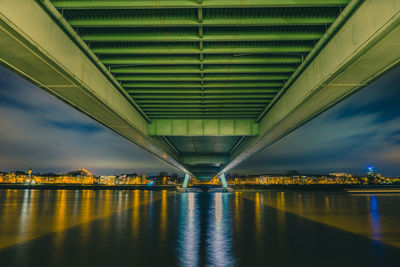 Illuminated bridge over river against sky in city