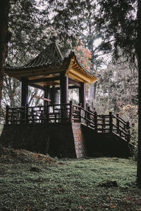 Gazebo on field by house in forest