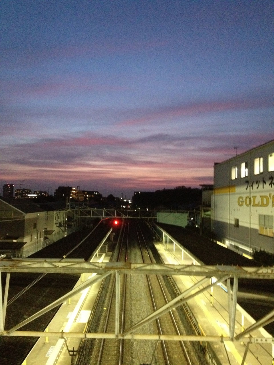 railroad track, transportation, rail transportation, public transportation, railroad station, railroad station platform, architecture, built structure, sky, building exterior, illuminated, city, high angle view, train - vehicle, sunset, mode of transport, dusk, travel, city life, train