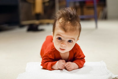 Portrait of cute baby boy lying on floor at home