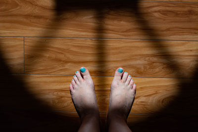 Low section of woman standing on wooden floor