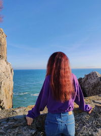 Rear view of woman looking at sea shore against sky