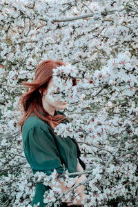 Young woman looking away while standing on field