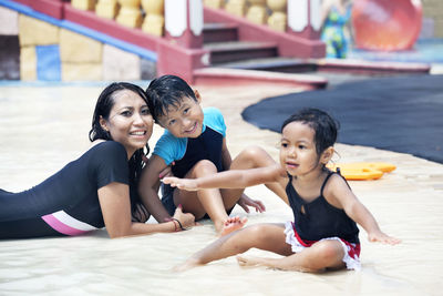 Portrait of mother with son and daughter in swimming pool at water park