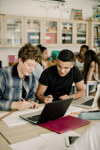 Male students studying while female friends sitting in background