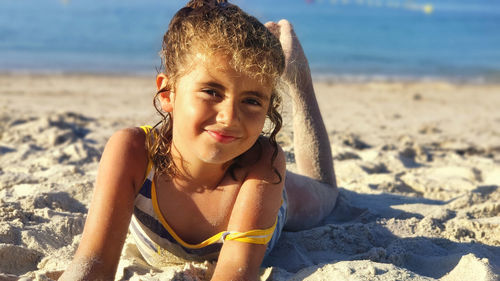 Little girl enjoying in the sand a day at the beach in summer