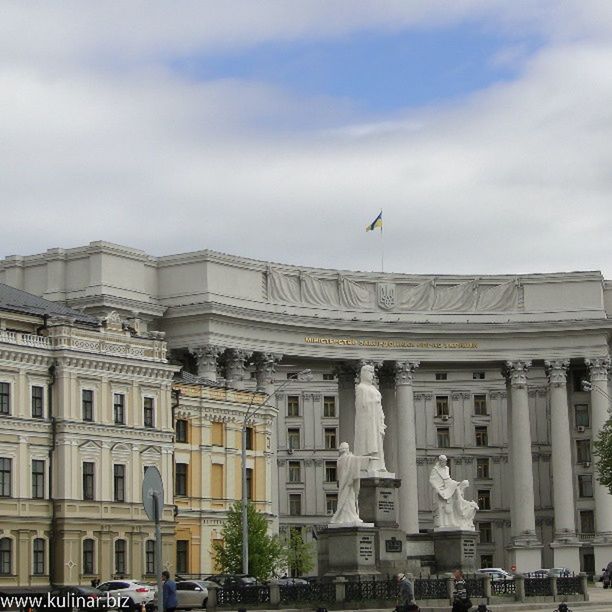 architecture, built structure, building exterior, sky, low angle view, city, bird, cloud - sky, building, flying, cloudy, day, outdoors, incidental people, cloud, architectural column, travel destinations, window, city life, facade