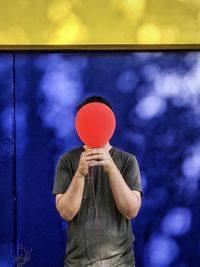 Man holding umbrella standing against wall