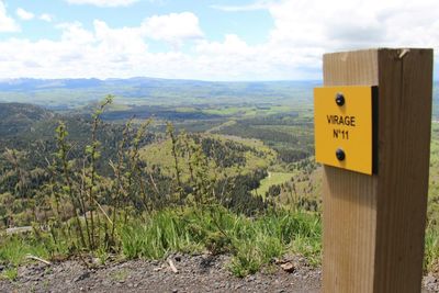 Close-up of information sign on landscape against sky