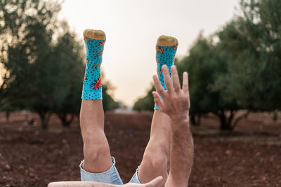 Man's legs and blurry hands up in the air with colourful socks and blue jeans short.