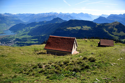 House on field by mountains against sky