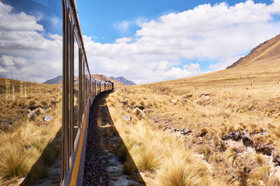 Panoramic view of road amidst field against sky