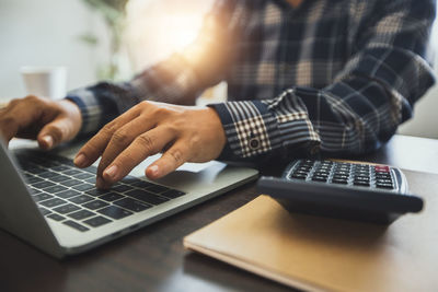 Midsection of man using laptop on table