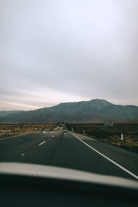 Road against sky seen through car windshield