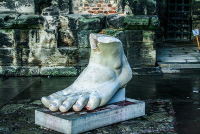 Statue by fountain against wall