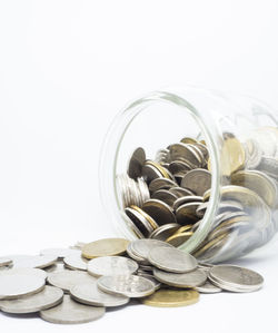 Close-up of coins in jar against white background