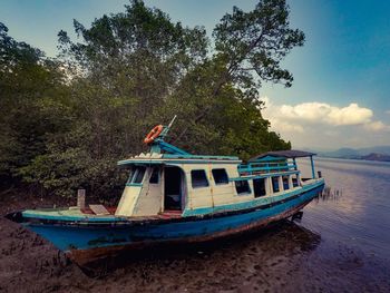 Boat moored on beach against sky