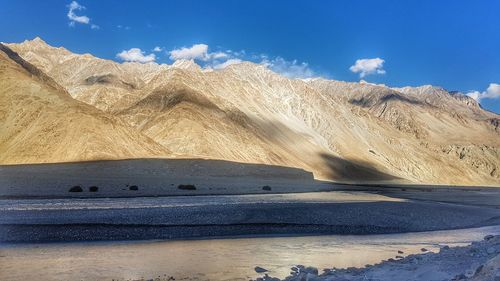 Scenic view of desert against cloudy sky