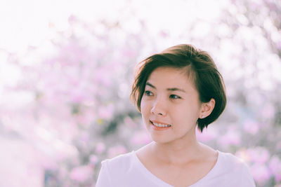 Portrait of smiling woman against pink flower