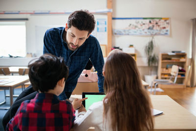 Teacher discussing with students using digital tablet in classroom