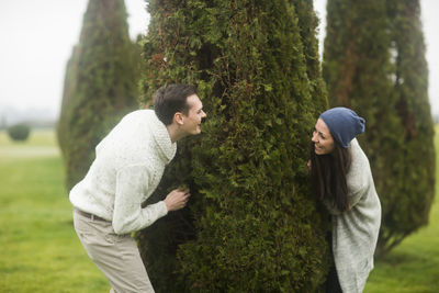 Young couple outside playing a game around a tree