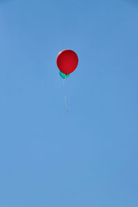 Two helium balloons flying towards blue sky