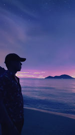Silhouette person standing by sea against sky during sunset